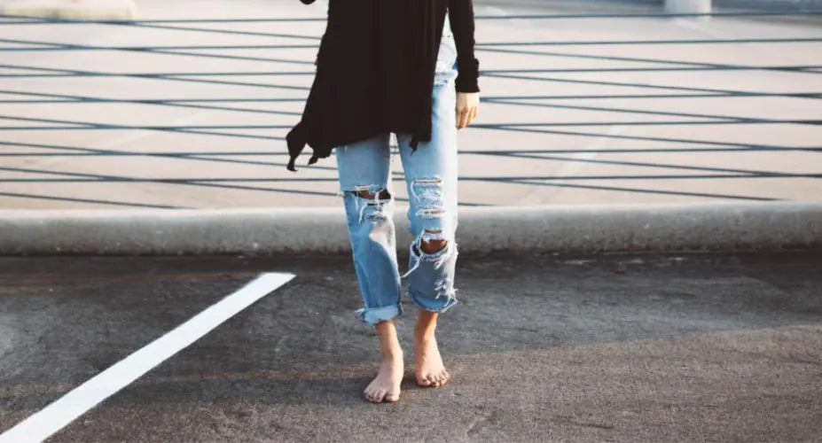 A woman walks barefoot across a parking lot